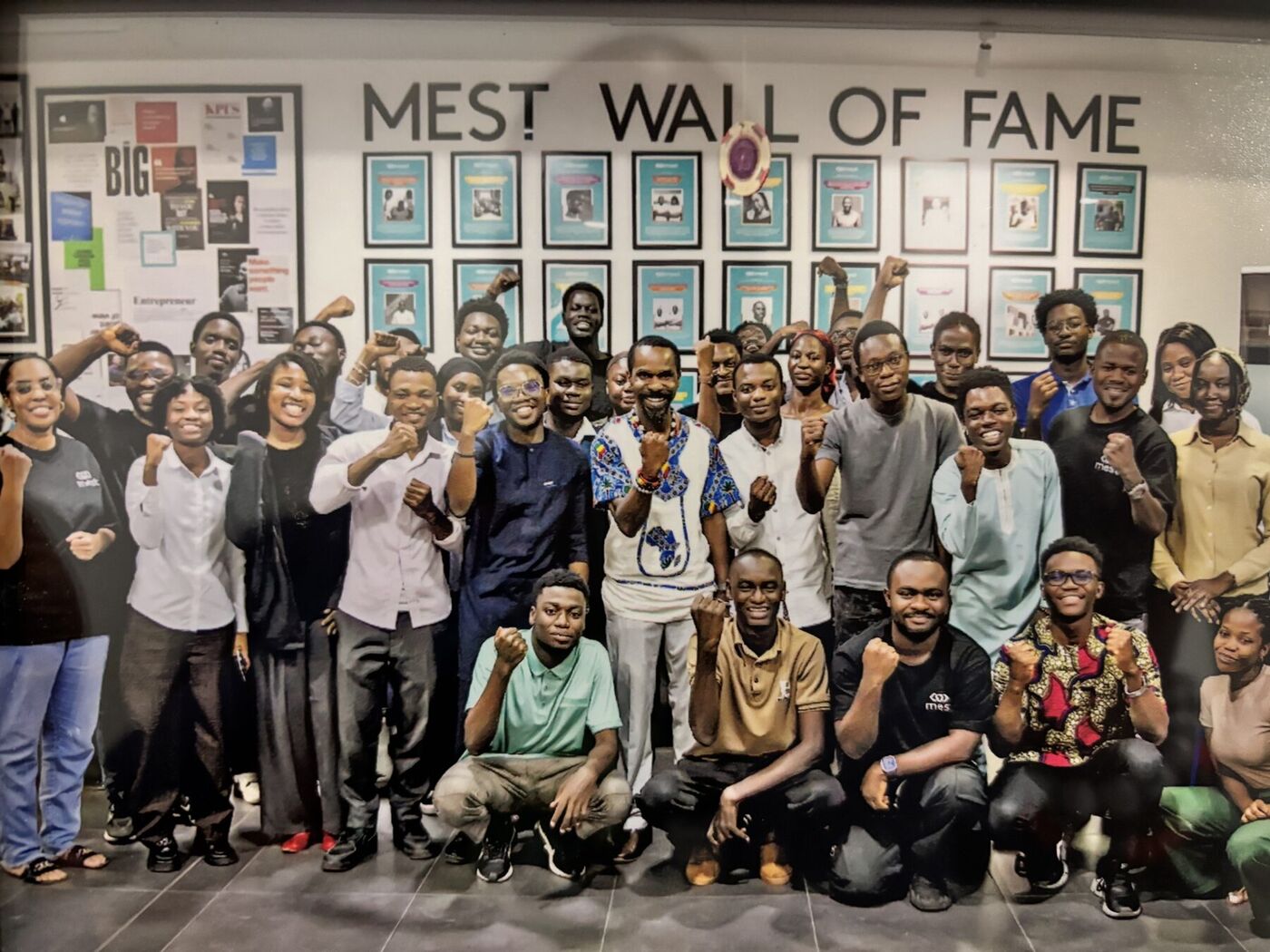 The MEST Class of 2026 and program staff gathered for a group photo in front of the MEST Wall of Fame.